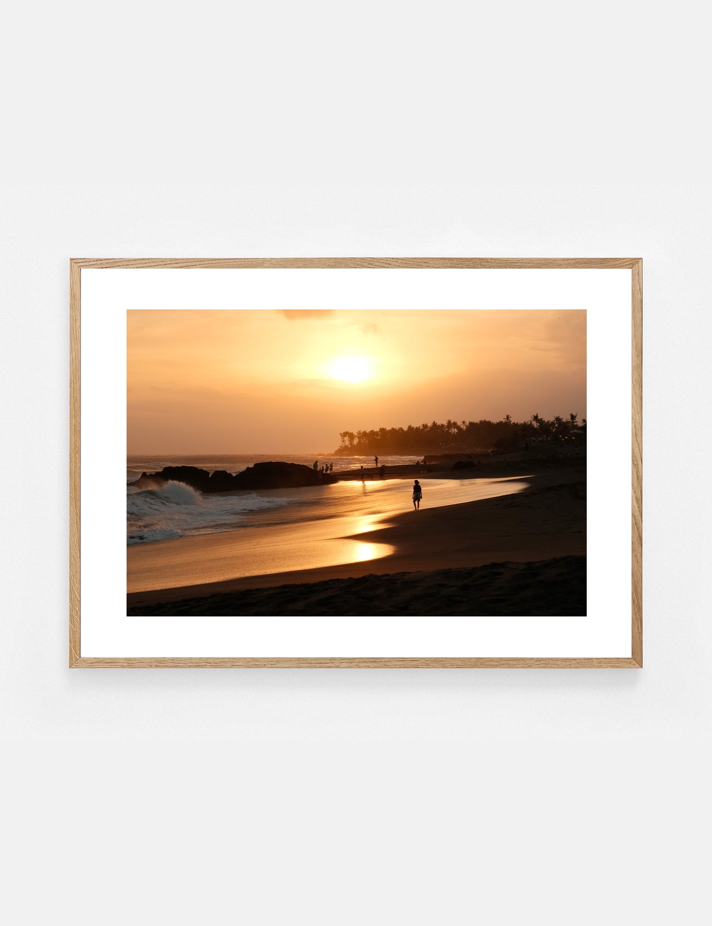 Framed artwork of a sunset over a beach with a person walking on the sand.