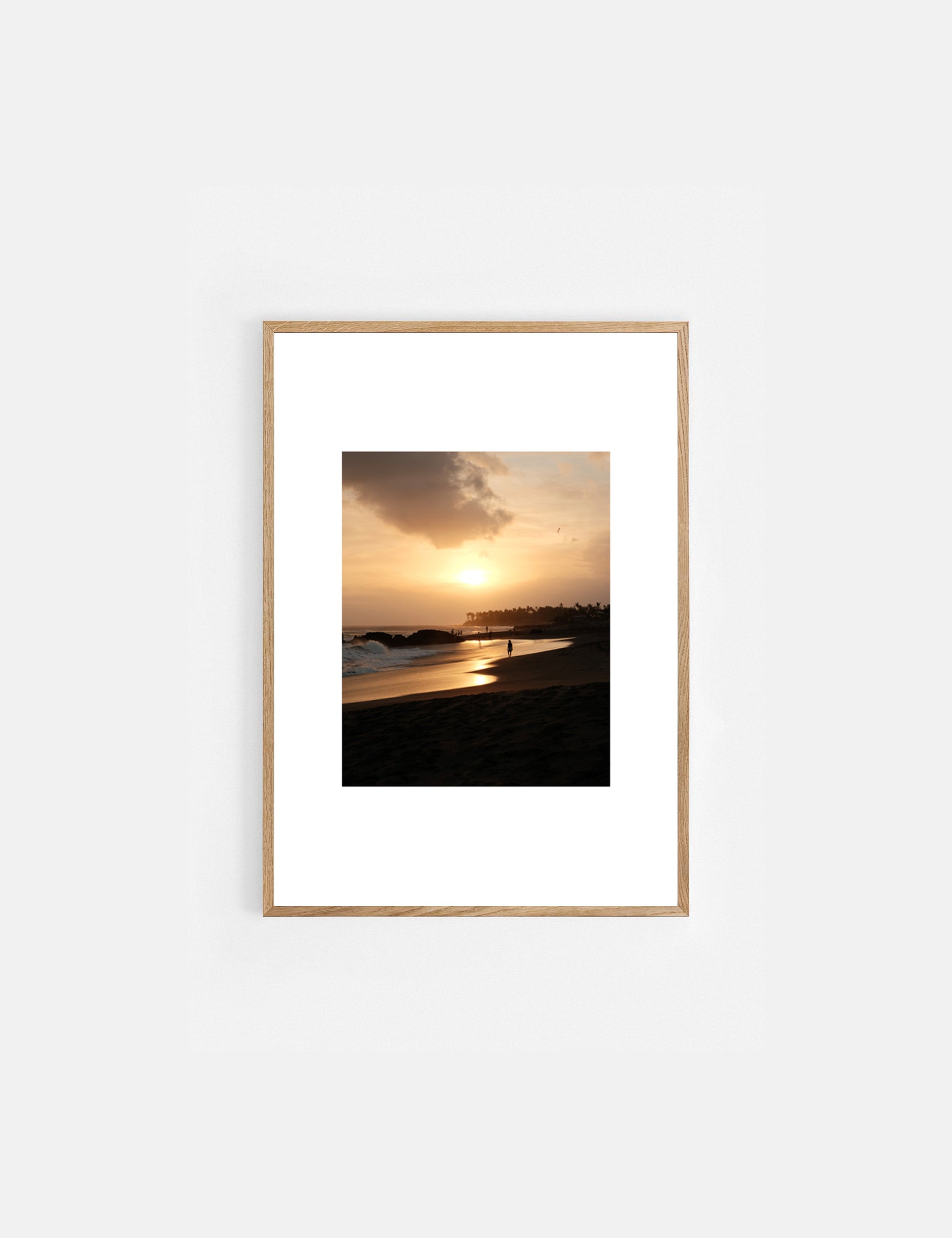 Framed artwork of a sunset over a beach with a wooden frame on a white background