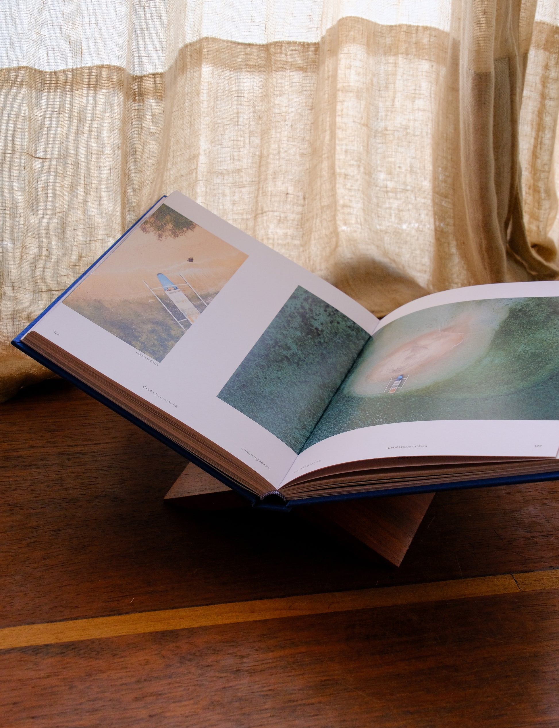 Open book on a wooden surface with a curtain in the background